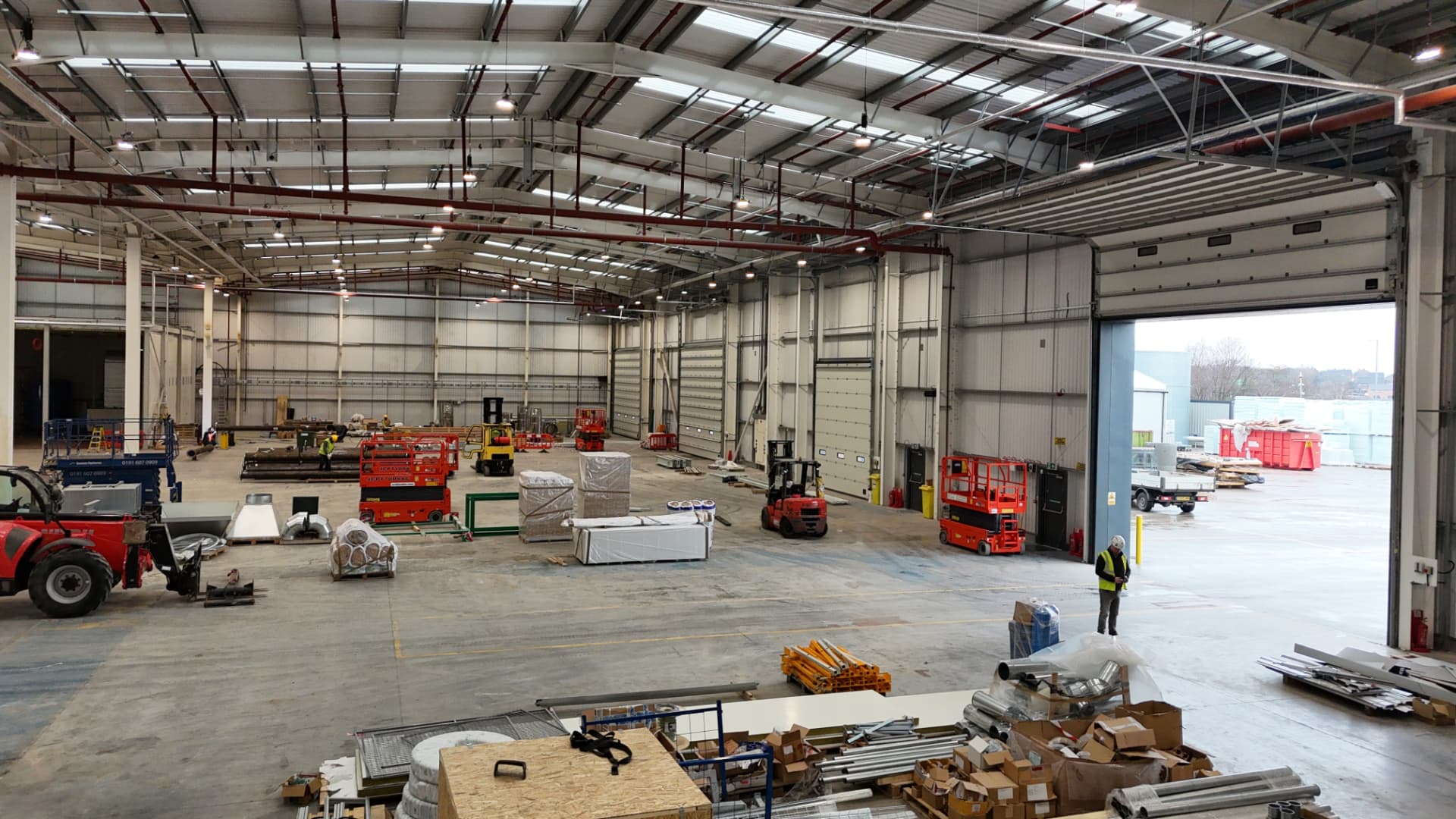 Workers and access equipment inside an active warehouse