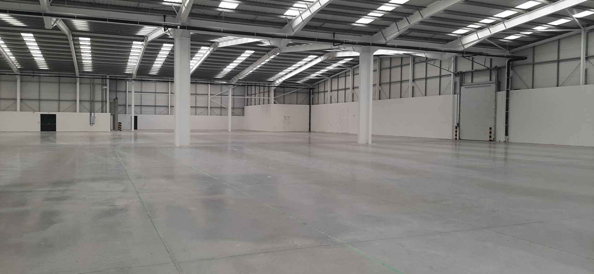 Empty industrial warehouse with white steel frame and polished concrete floor